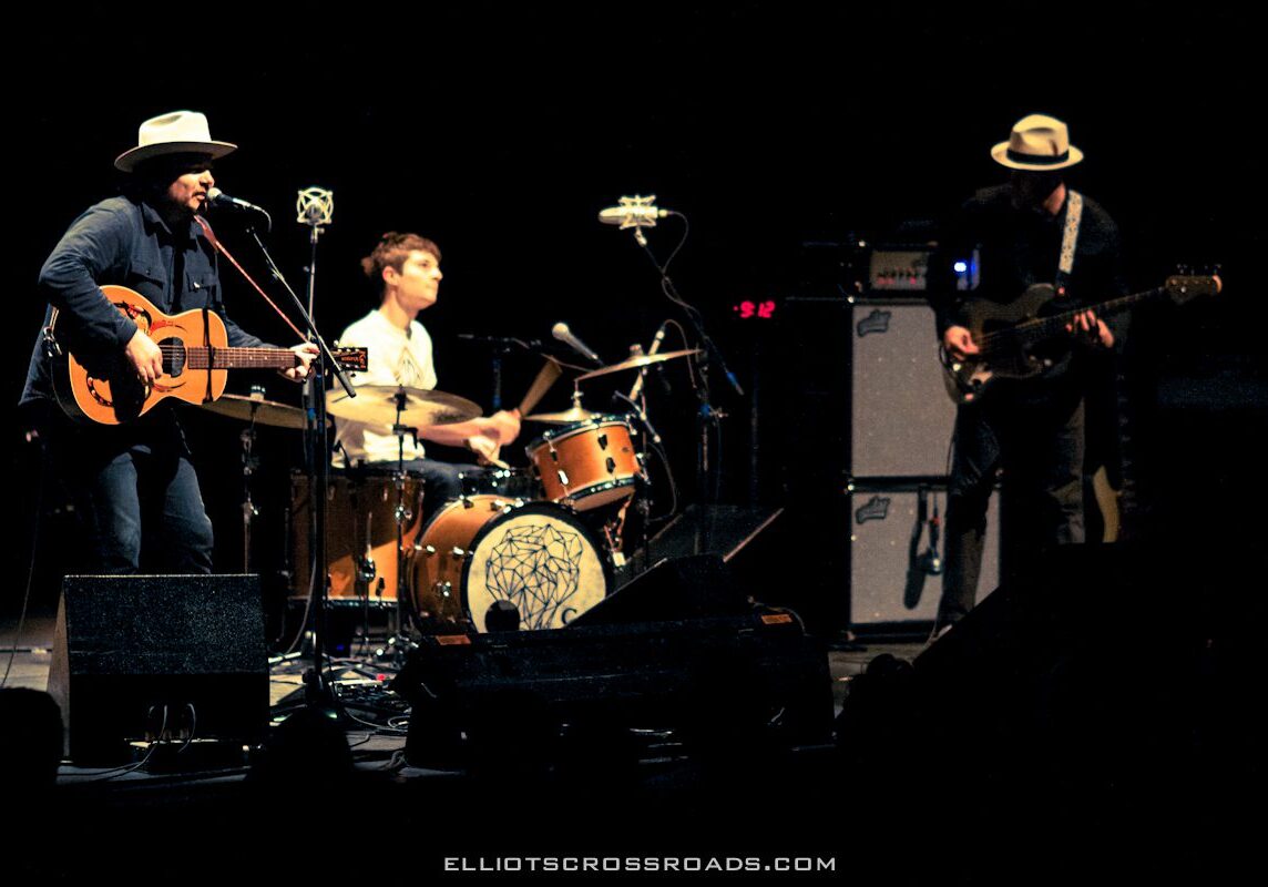 Band performing live on stage with instruments.
