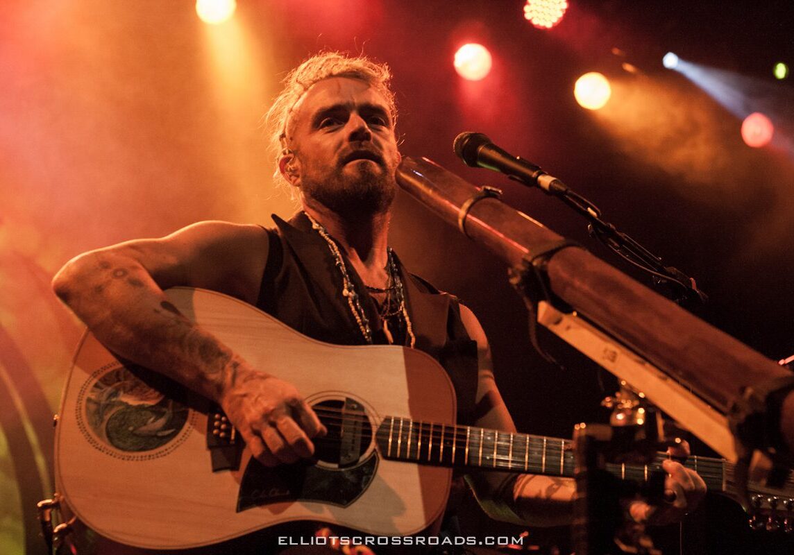 Musician performing with guitar on stage.