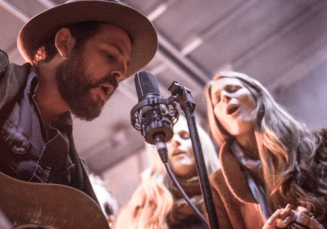 Musicians singing and playing guitar on stage.