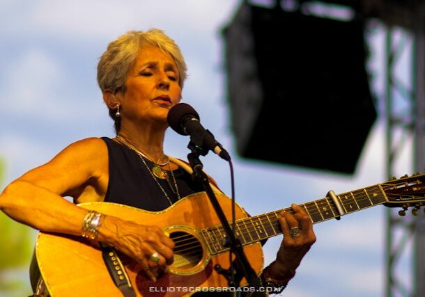 Woman performing with guitar on stage.