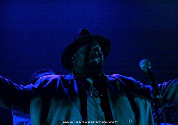 Singer performing passionately under blue lights.