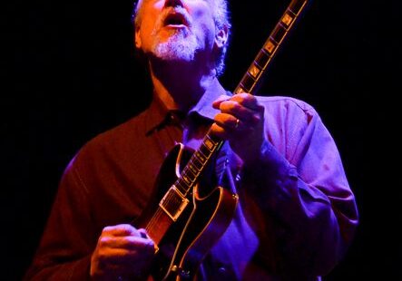 Musician passionately playing electric guitar onstage.