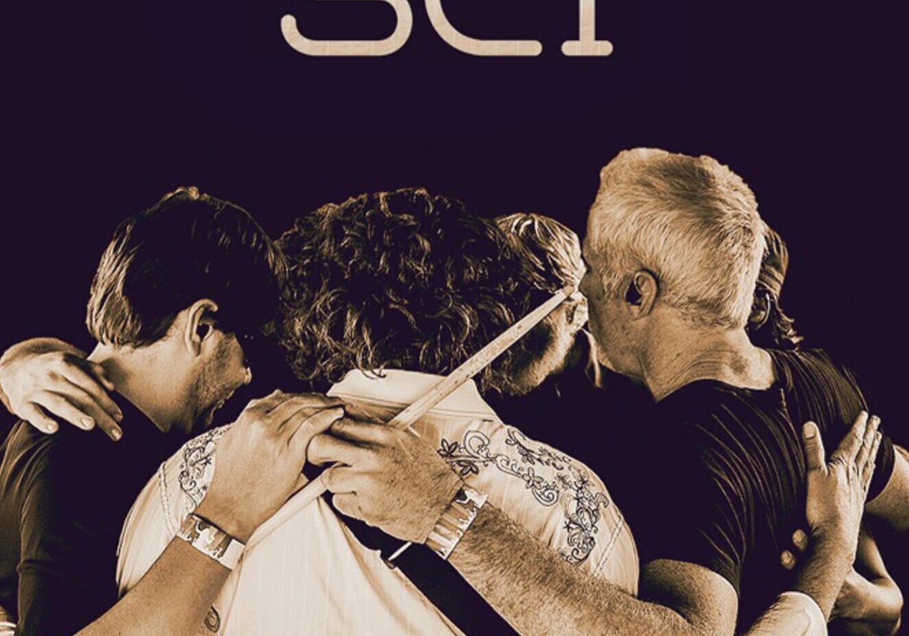 Band members embracing on magazine cover.