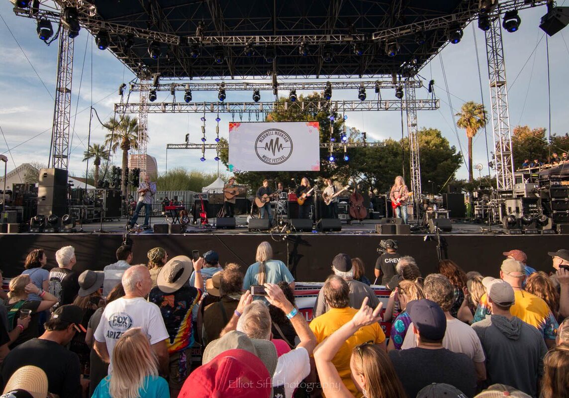 Outdoor concert with crowd and stage lights.