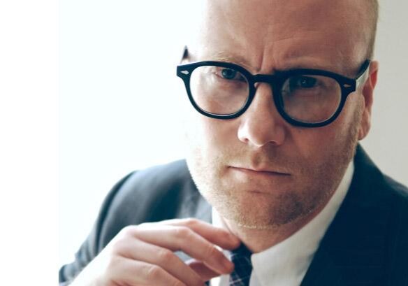 Man wearing glasses and suit, looking serious.