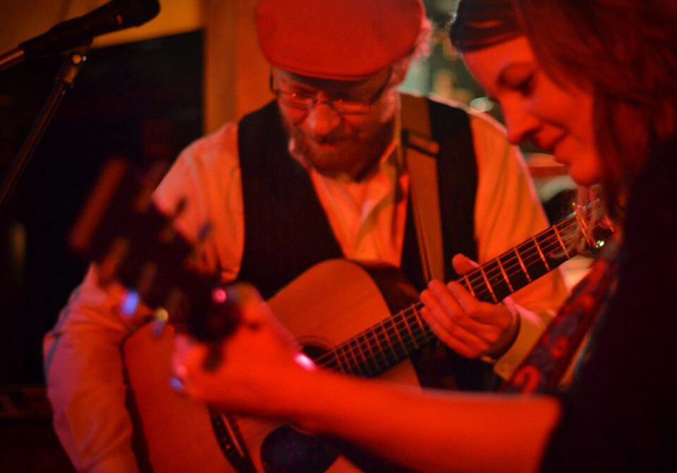 Musicians playing guitars on stage together.