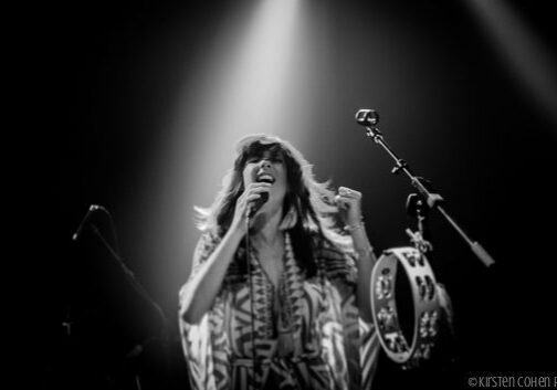 Singer performing on stage with tambourine.
