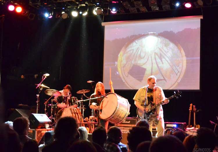 Band performing live on stage with instruments.