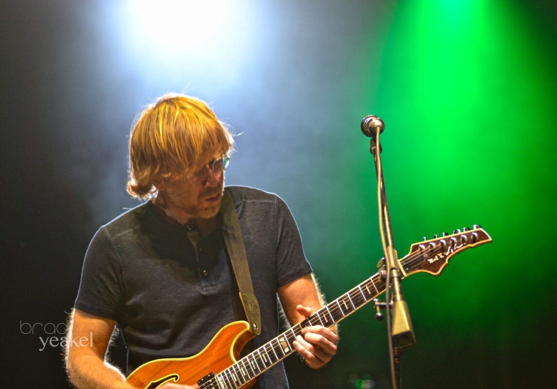 Guitarist performing under colorful stage lights.