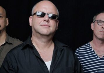 Three men posing against a dark background.
