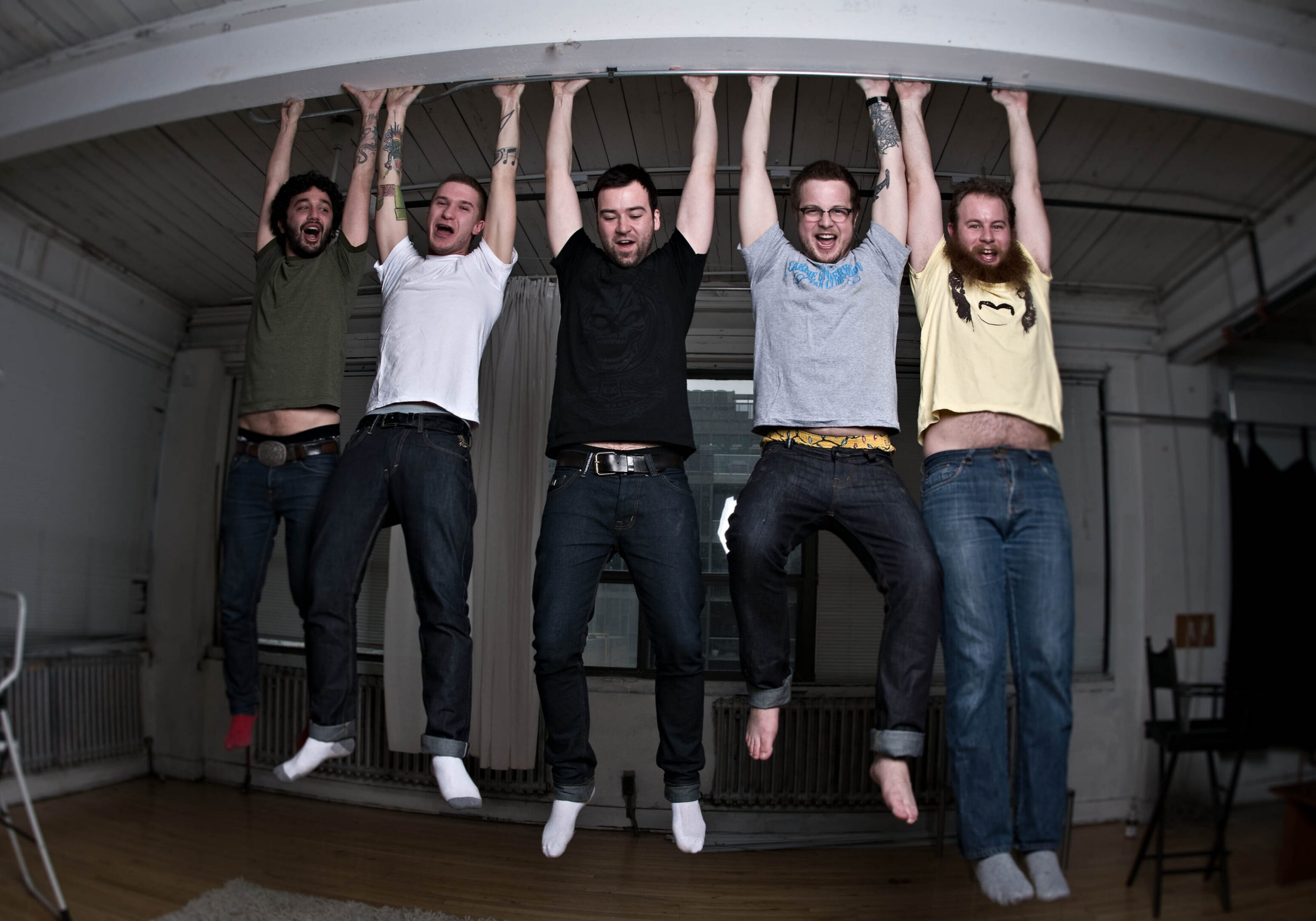 Five people hanging from a ceiling beam.