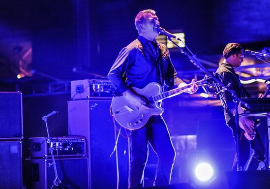 Band performing live on stage with guitars.
