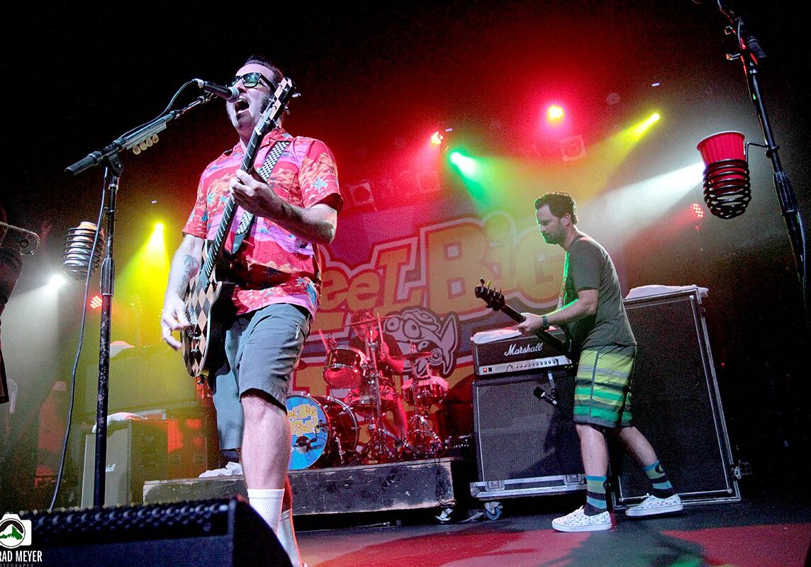 Band performing energetically on colorful stage.