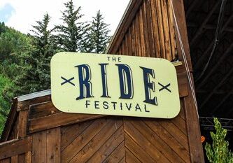 The Ride Festival sign with trees background.