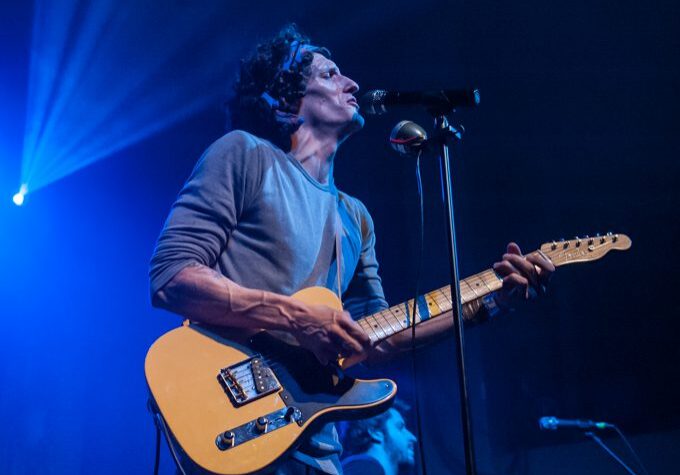 Musician performing on stage with guitar.