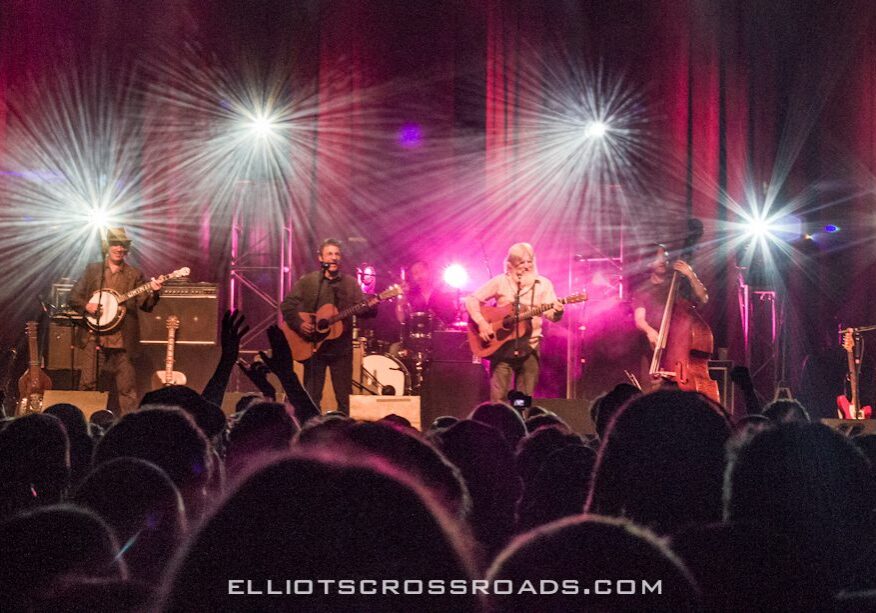 Band performing on stage with bright lights.