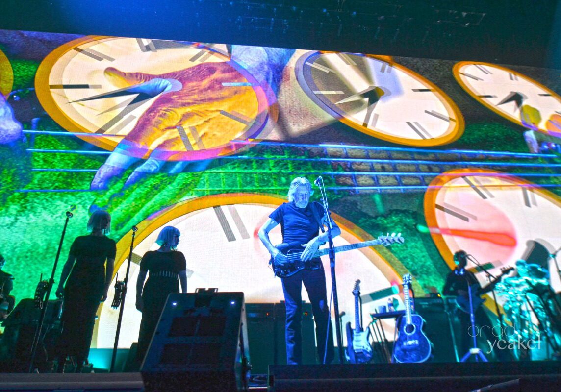 Concert stage with clocks and musicians performing.