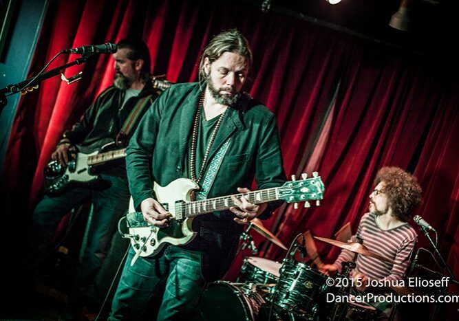 Band performing live with guitar and drums.