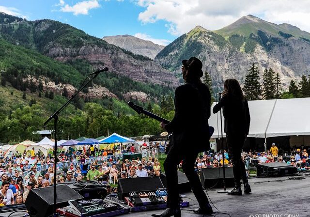 Outdoor concert with mountainous background scenery.