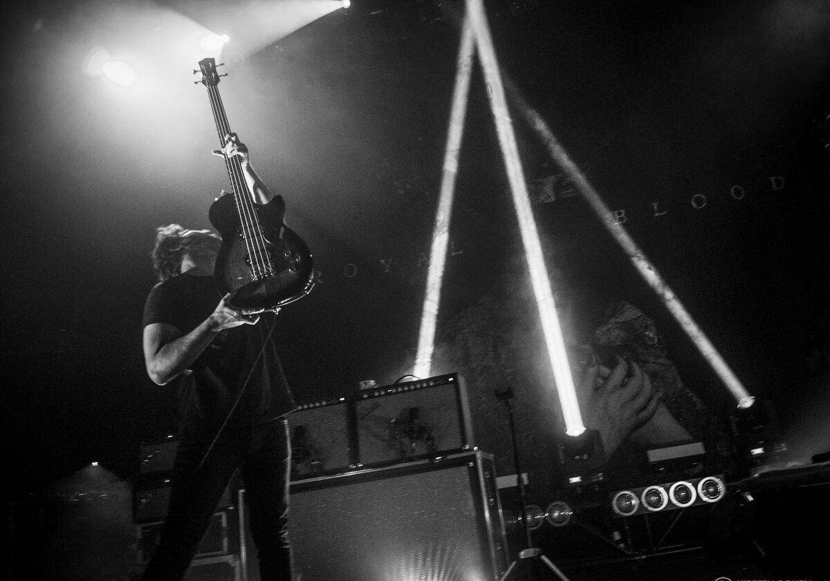 Musician performing energetically with guitar on stage.