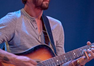 Man playing acoustic guitar on stage.