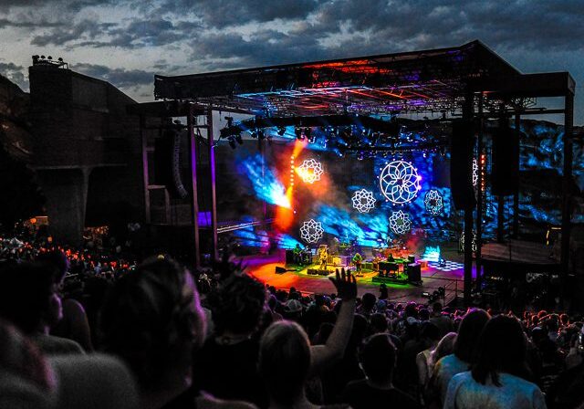 Outdoor concert with vibrant stage lighting display.
