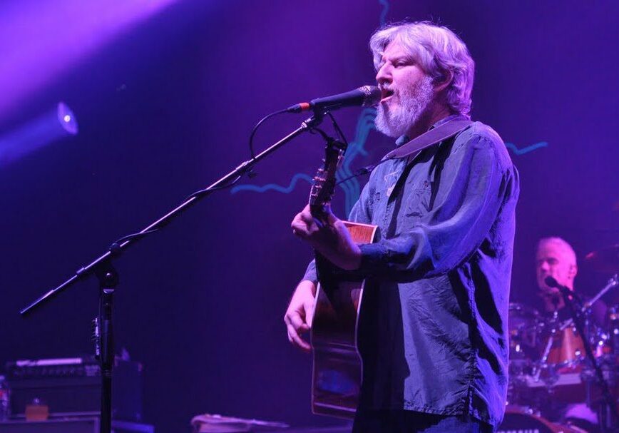 Musician performing on stage with guitar.