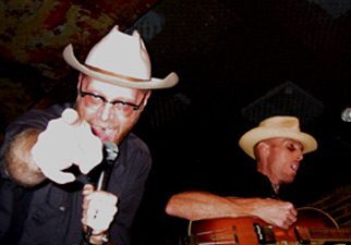 Two musicians performing with hats and guitars.