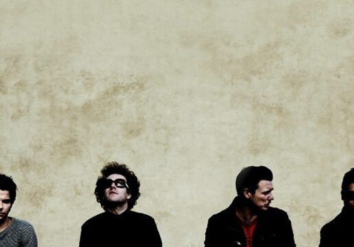 Four people sitting against a textured wall.