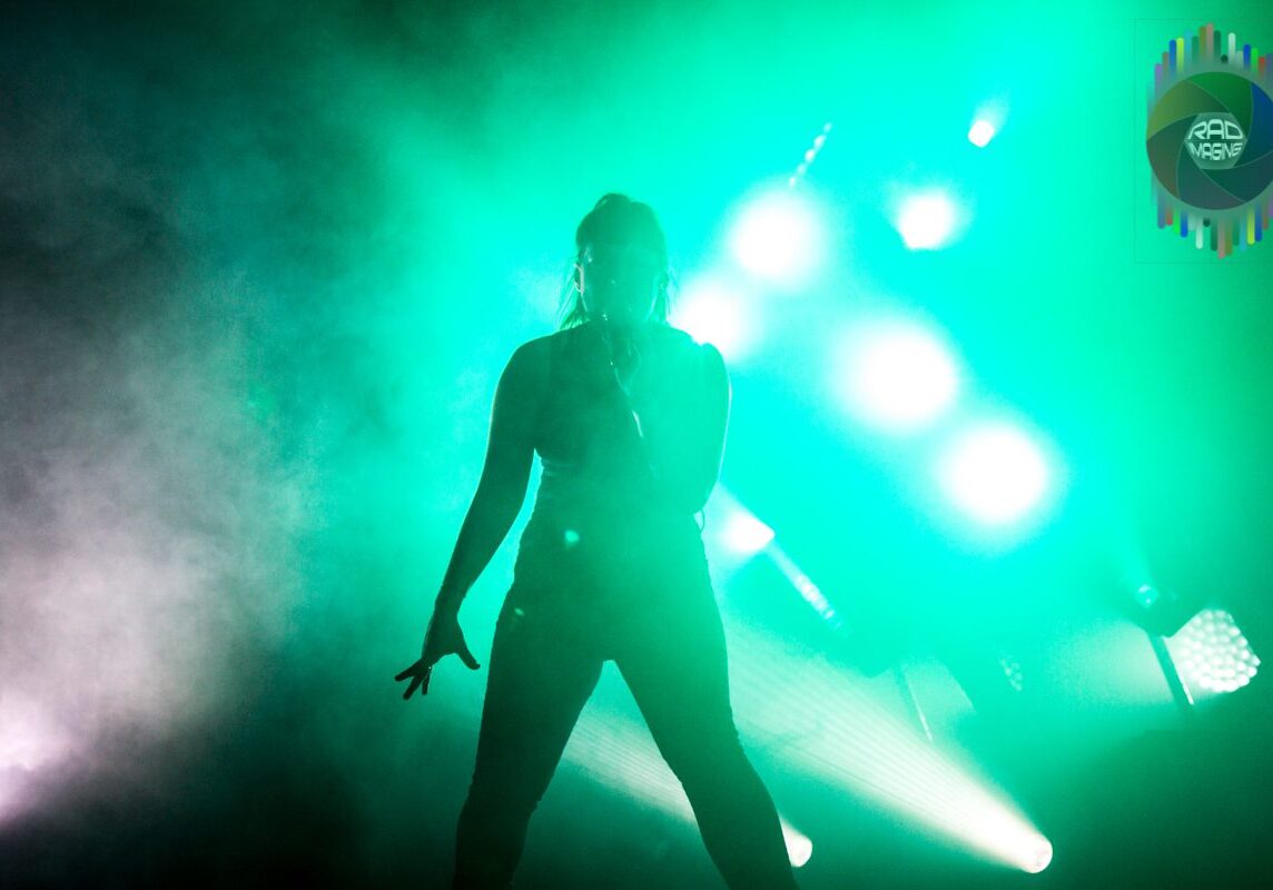 Performer silhouetted against green stage lights.