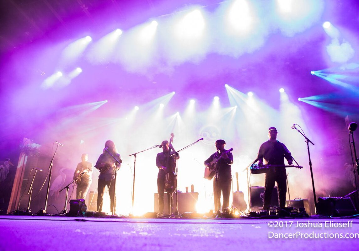 Band performing on stage with colorful lights.