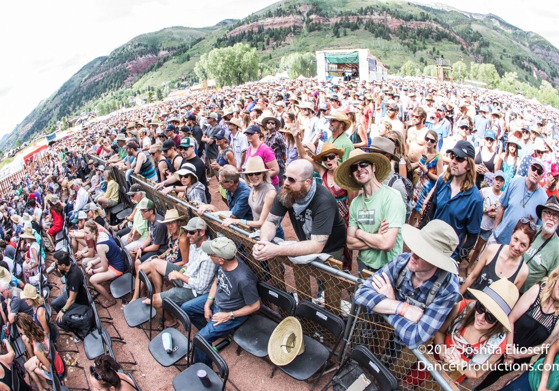 Outdoor music festival crowd with mountain backdrop.