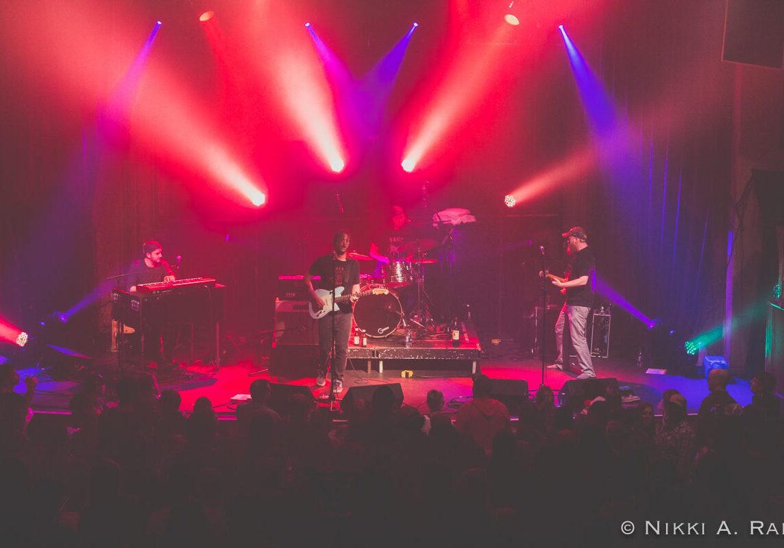 Band performing on stage with colorful lights.