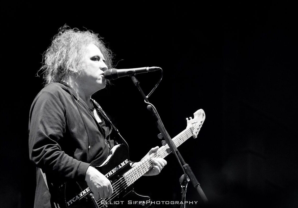 Musician performing on stage with guitar.