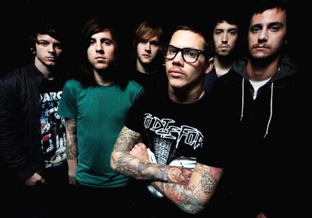 Six men standing in a dark setting.