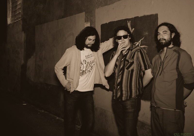 Three men standing in dimly lit alley.