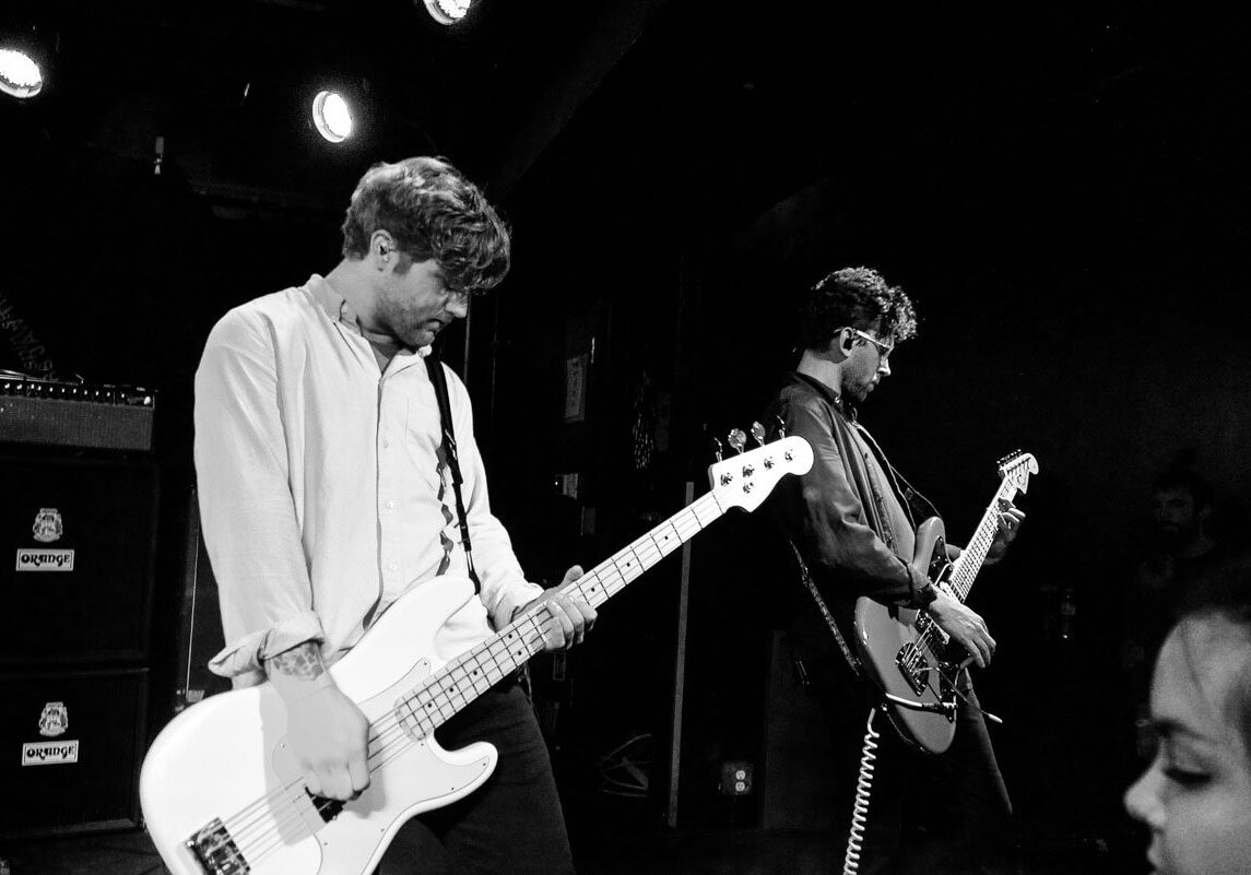 Two musicians performing on stage with guitars.