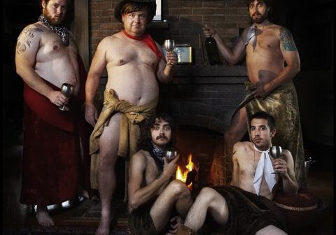 Five men posing in front of fireplace.