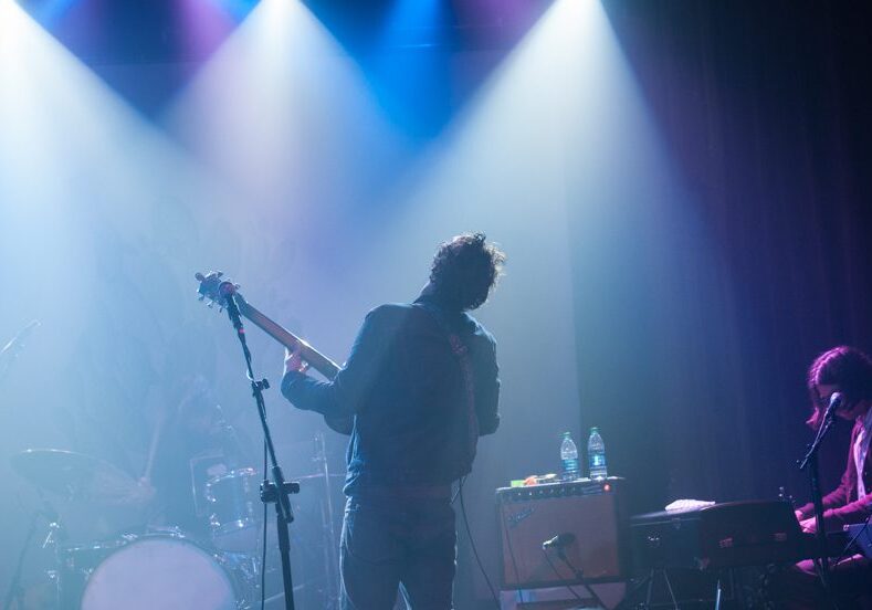 Musicians performing on stage with colorful lights.