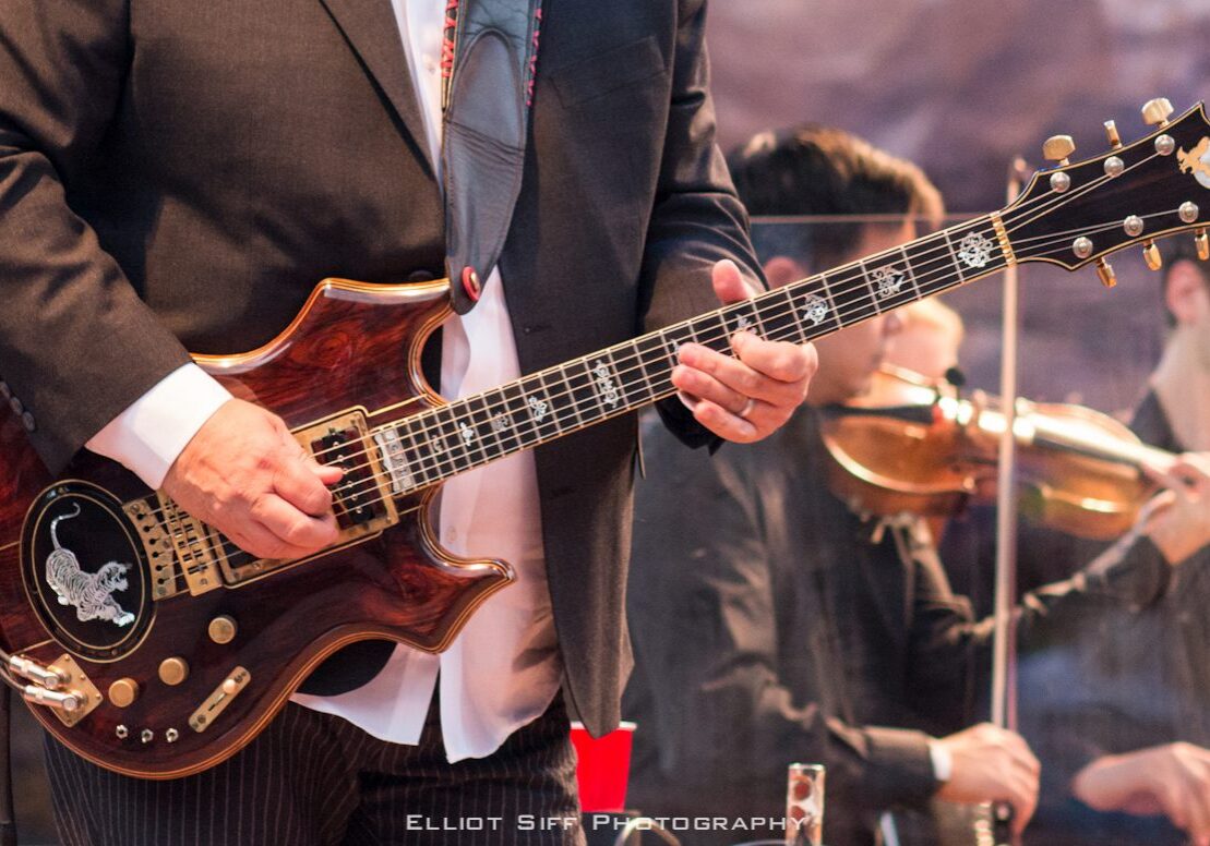 Musician playing electric guitar on stage.