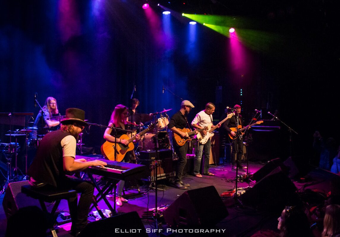 Band performing on stage with colorful lights.