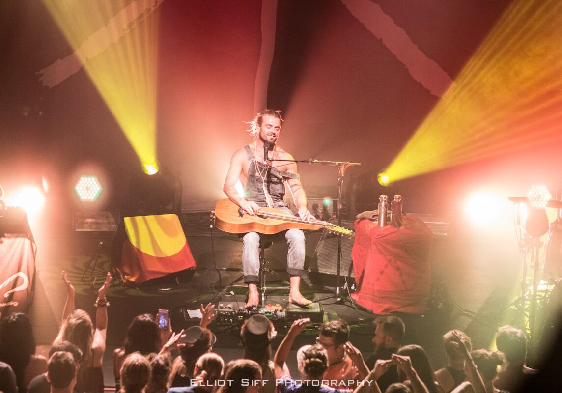 Musician performing on stage with guitar.