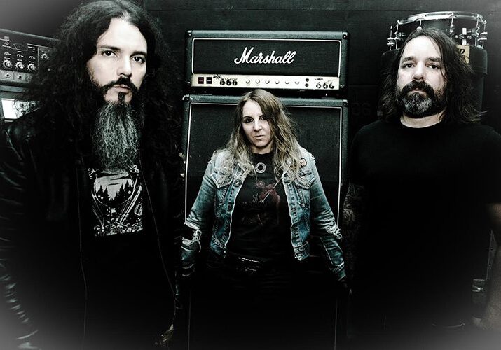 Three musicians standing by Marshall amplifier.