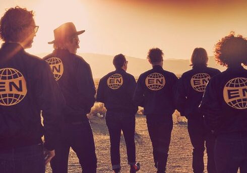Group walking in desert wearing matching jackets.