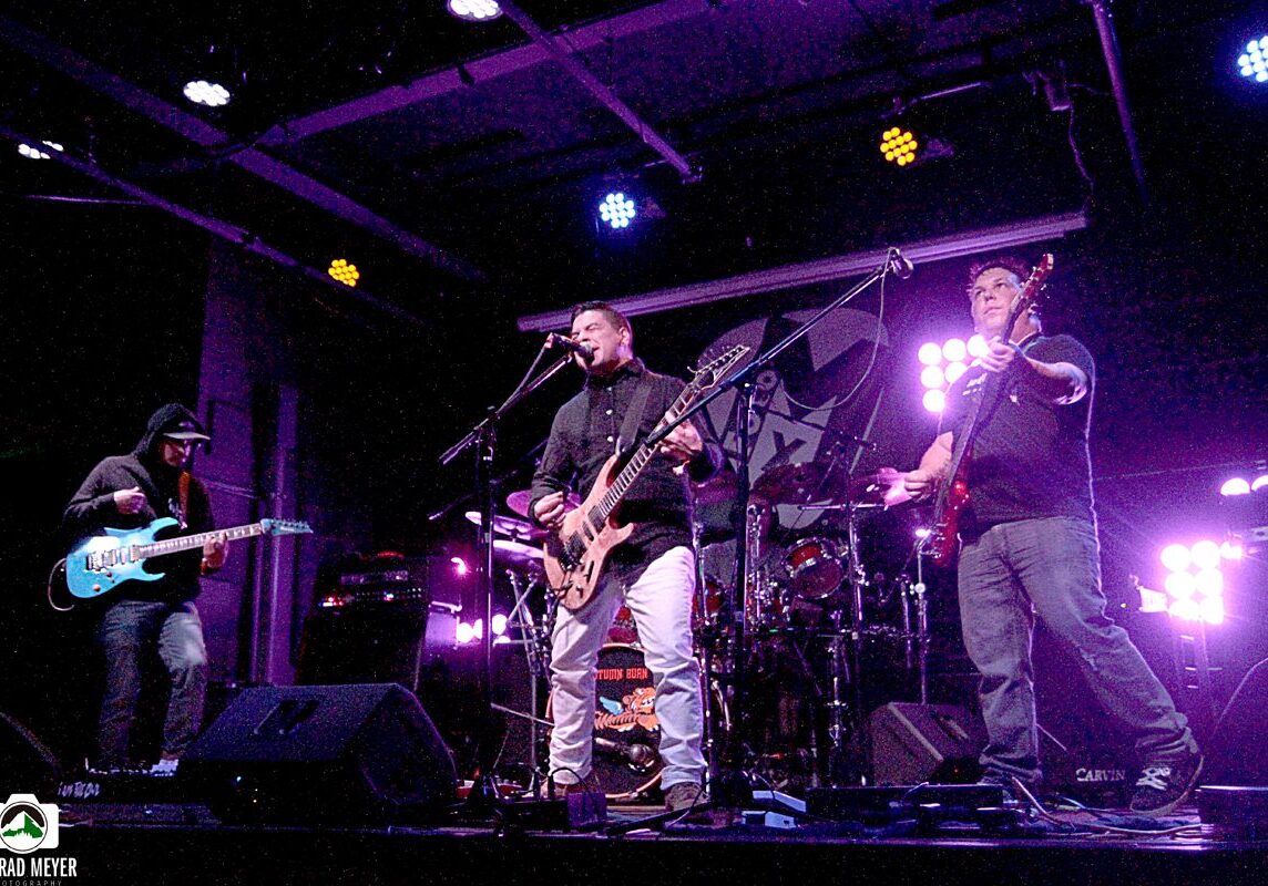 Band performing live on stage with instruments.