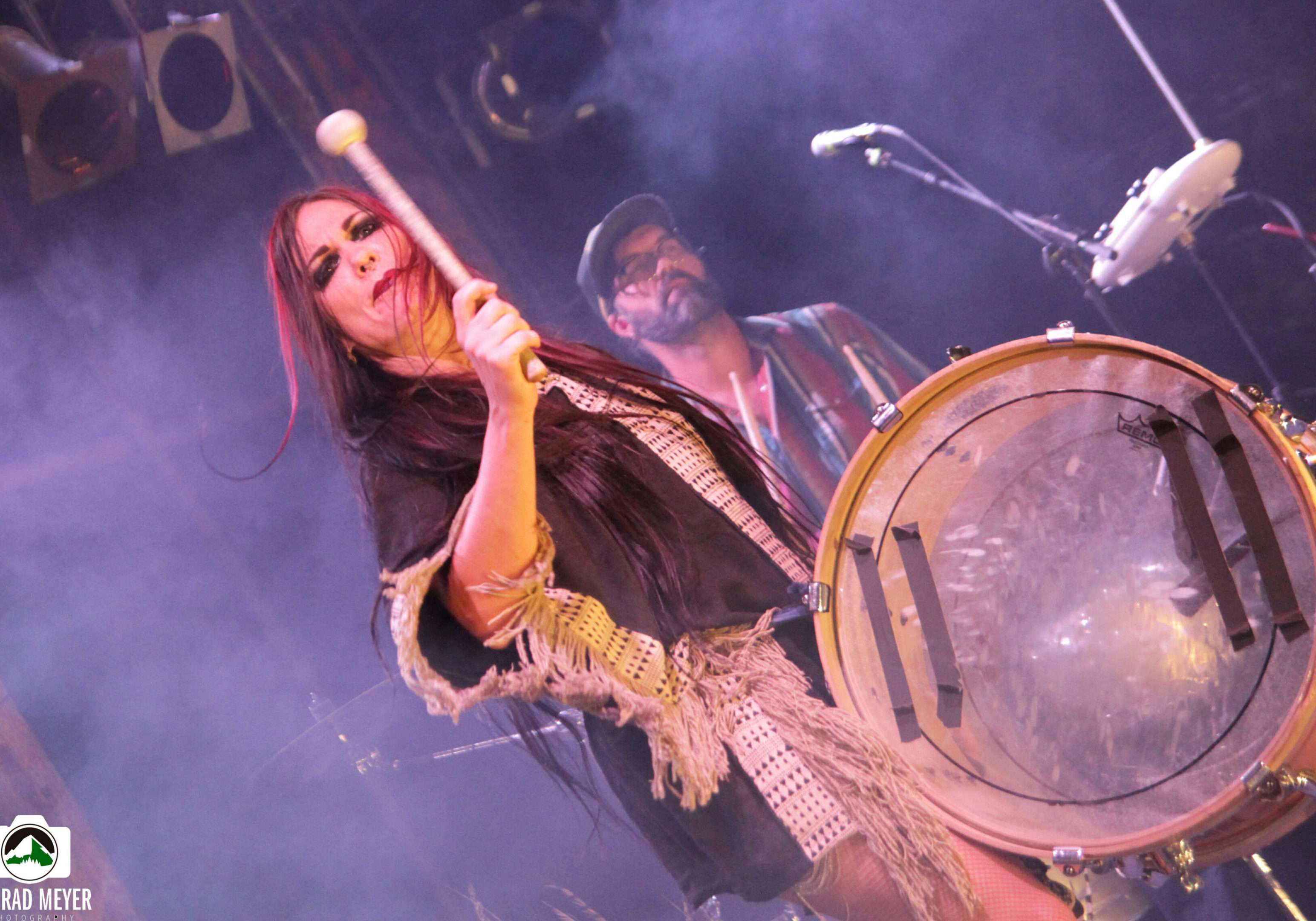 Woman playing drum on stage, lively performance.