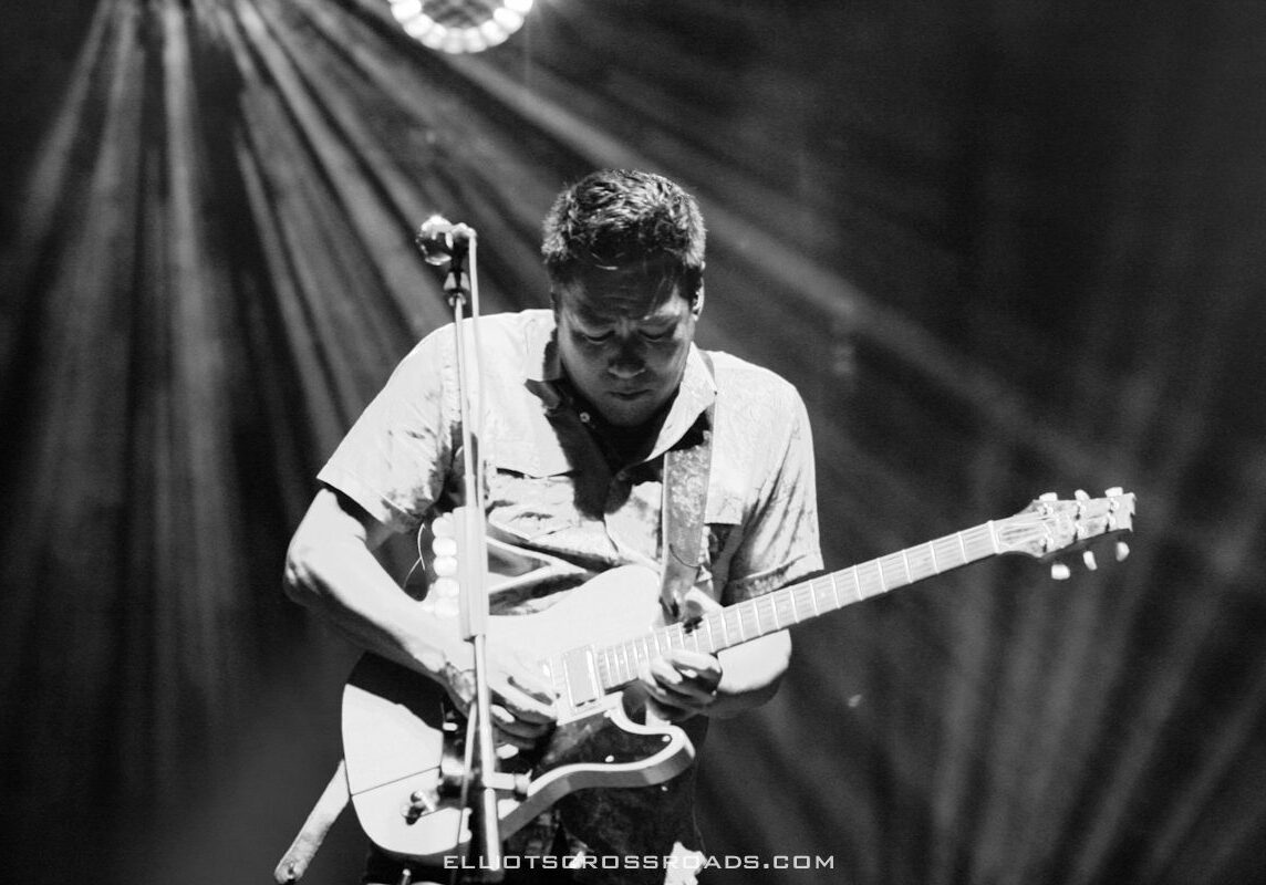Musician playing electric guitar on stage.