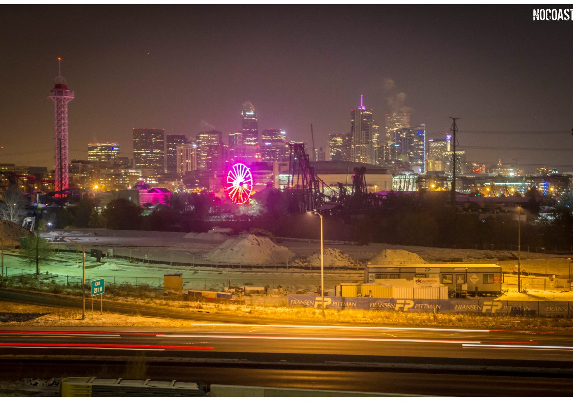City skyline at night with illuminated Ferris wheel.