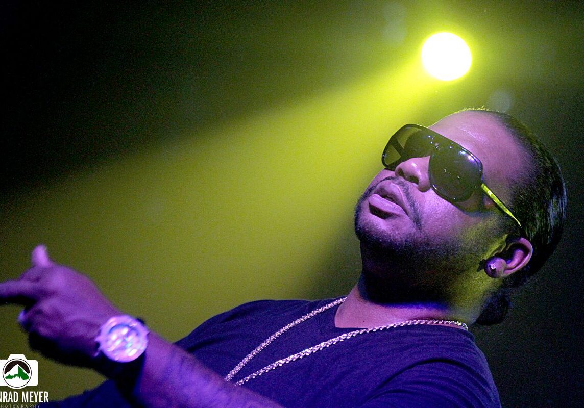 Man performing on stage under yellow light.