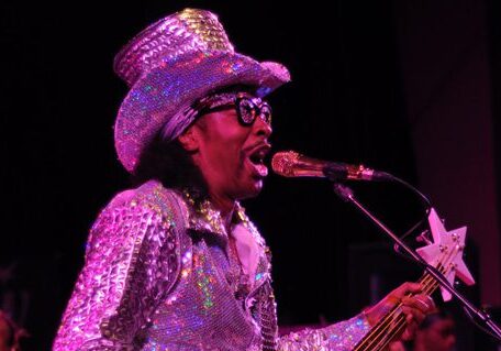 Musician performing in sparkly outfit on stage.